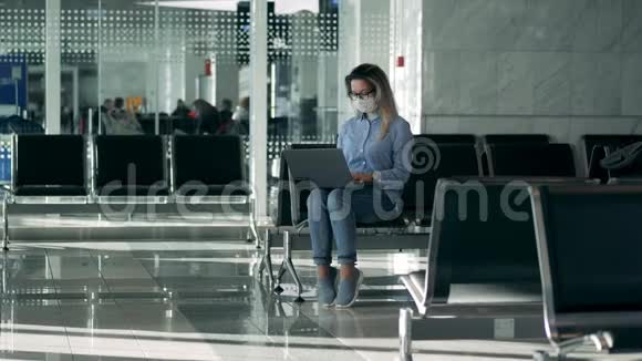 机场休息室一位女士戴着医用口罩使用笔记本电脑视频的预览图