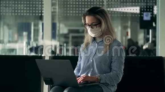 一位女士戴着医用口罩和眼镜在笔记本电脑上打字视频的预览图
