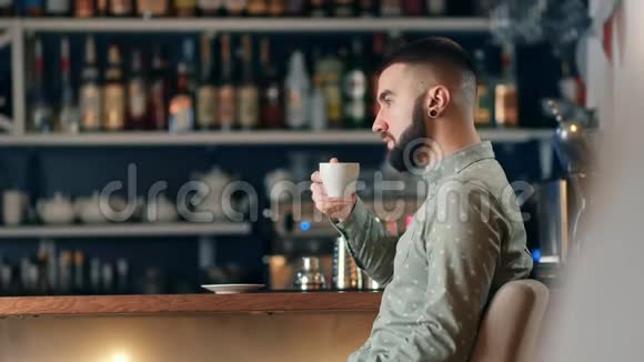 坐在桌子上的自助餐厅喝咖啡的男人长胡子中型摄影机拍摄视频的预览图