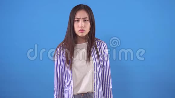 年轻的亚洲女人在蓝色背景上竖起大拇指视频的预览图
