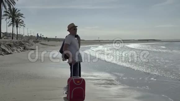 旅行者带着一个红色的手提箱来到海边度假积极的情绪视频的预览图
