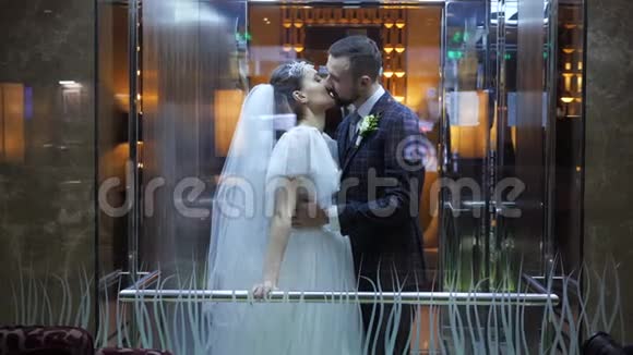 在乌克兰哈尔科夫宫酒店的电梯里亲吻婚礼快乐的夫妇有胡子的新郎拥抱并亲吻他视频的预览图