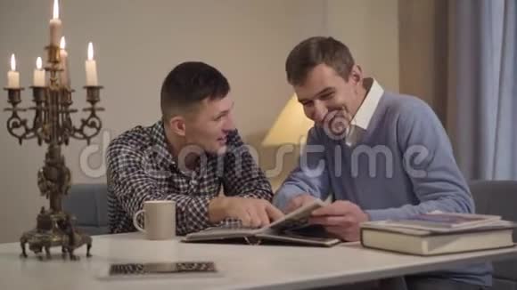 两个成年白种人晚上坐在室内聊天快乐的年轻人和他的中年父亲视频的预览图