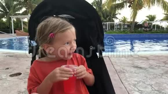 小女孩坐在婴儿车里喝柠檬水视频的预览图