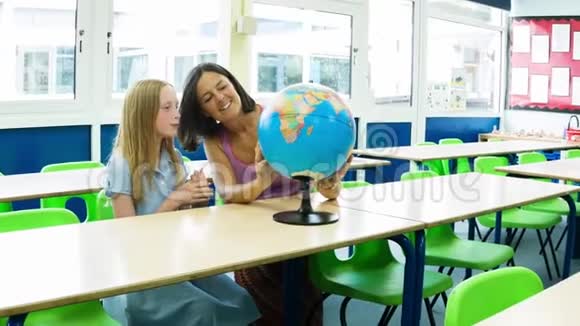 白人小学女孩和她的老师看着一个地球视频的预览图