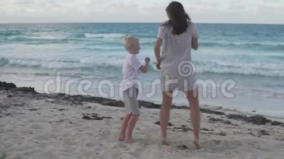 妈妈和儿子在海边的海滩上跳舞很开心视频的预览图