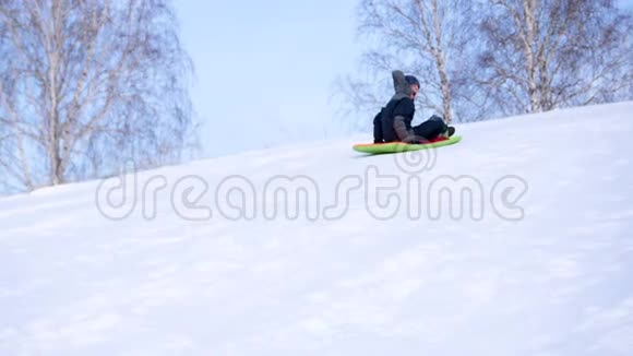 一个孩子在雪山上骑马和玩耍慢动作雪的冬季景观户外运动视频的预览图