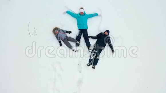 一个有孩子的家庭在森林的空地上做一个雪天使的身影一个女孩和视频的预览图