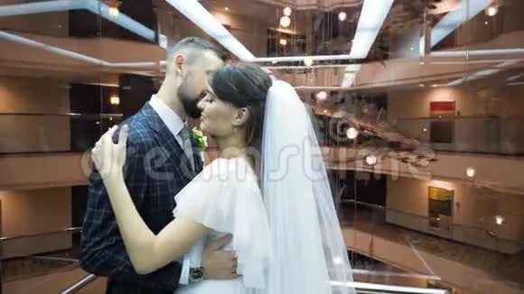 穿着西装的蓄胡子新郎亲吻穿着婚纱的漂亮新娘坐在哈科夫舒适漂亮的电梯里视频的预览图