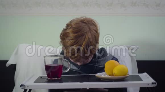 红头发的白人男孩抬头看着镜头不满意的生病孩子坐在家里的床上视频的预览图