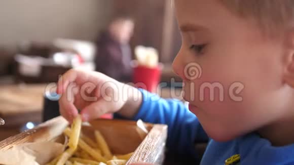一个在快餐店的孩子在盘子里吃炸土豆面的特写油煎土豆片视频的预览图