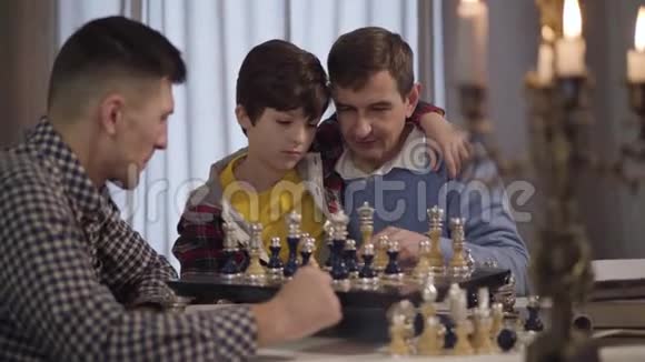 快乐的白种人祖父和孙子和男孩的年轻父亲下棋的肖像自信的小男孩和视频的预览图