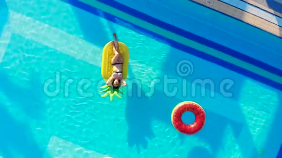 一个女孩躺在一个有橡胶圈的旅馆游泳池里视频的预览图