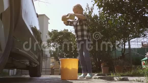 女孩在洗车后把海绵扔进一桶肥皂水里视频的预览图