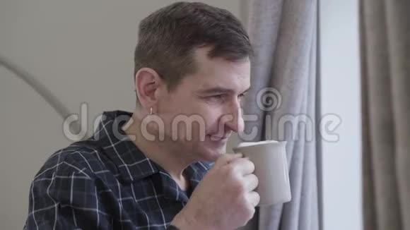成年白种人的近脸有耳环的味道喝着早晨的咖啡积极的中年男子微笑视频的预览图