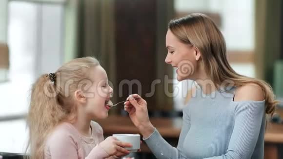 快乐的女人喂蛋糕给迷人的女婴笑着享受休息近距离拍摄4k红色相机视频的预览图