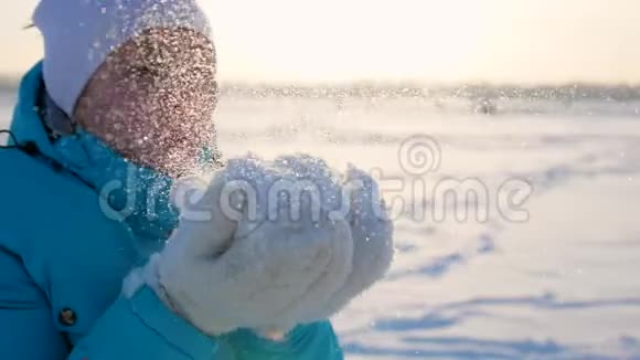 女孩用手吹雪花冬天散步视频的预览图