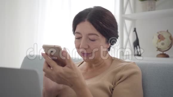 使用智能手机拍摄的高加索人女性的特写照片自信的中年退休人员轻触屏幕视频的预览图