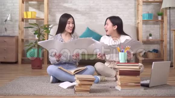 两个积极的亚洲学生正坐在地上扔纸视频的预览图