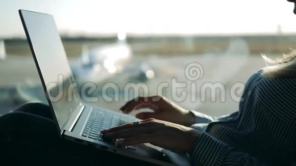 机场窗户旁的一位女士正在操作笔记本电脑视频的预览图