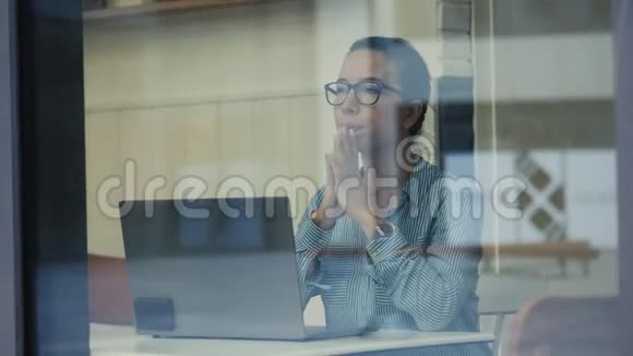 咖啡厅窗口和一位女士操作一台笔记本电脑通过它拍摄视频的预览图