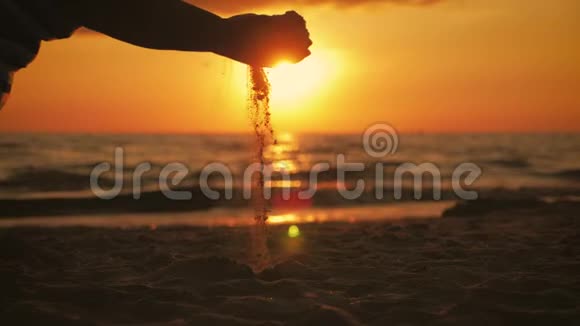 剪影的女人拿着沙子时间从你的手指滑过日落背景暑假海滩假期视频的预览图