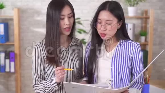 两名年轻的亚洲女职员近距离讨论文件视频的预览图
