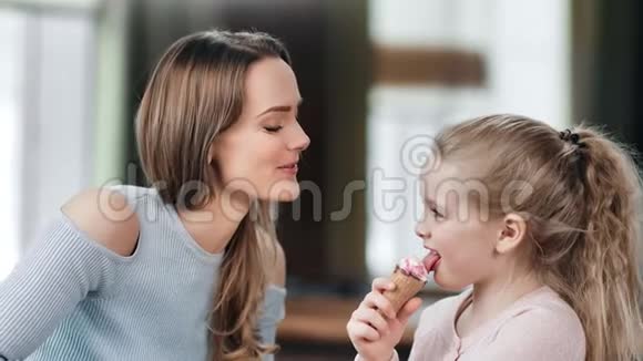 嘲笑年轻女人在吃冰淇淋的时候和女儿玩近距离拍摄4k红色相机视频的预览图