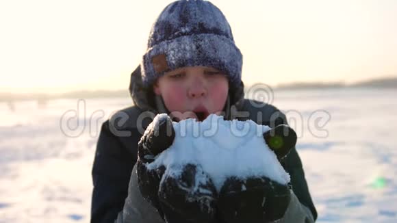 在日落特写镜头的背景下盖伊把手掌上的雪吹走视频的预览图