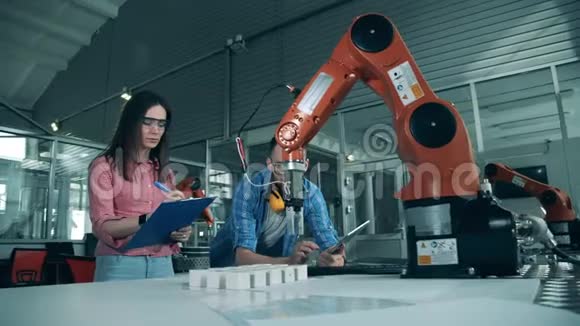 理工科学生正在监视一个机器人手臂重新定位物体视频的预览图