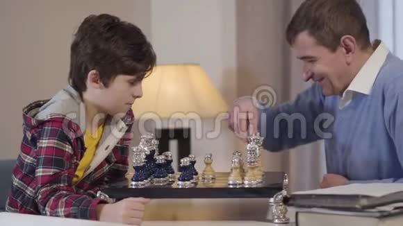 小白种人男孩和中年男子下棋祖父和孙子在家共度晚视频的预览图