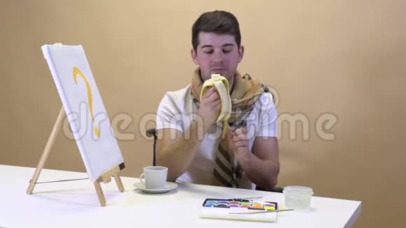 餐桌上的艺术家吃香蕉等待灵感视频的预览图