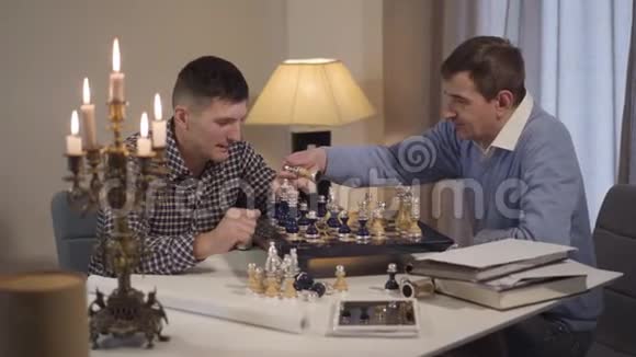 可爱的白种人黑发男孩卷发来到祖父和父亲下棋多代家庭视频的预览图