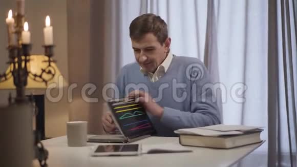 开朗的白种人成年男子关闭相册和平板电脑积极的中年男人坐在桌子旁视频的预览图
