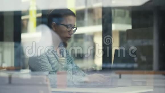 咖啡馆的窗户和一个正在用笔记本电脑工作的女人视频的预览图