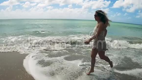 美丽的女人正缓慢地沿着海边奔跑视频的预览图