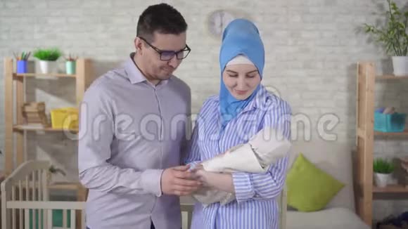 幸福的年轻穆斯林家庭带着新生婴儿看着镜头微笑视频的预览图