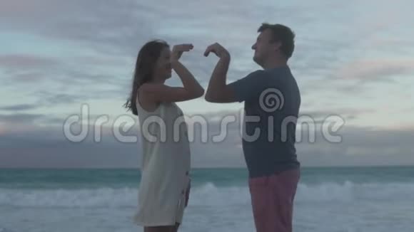 一对相爱的夫妇在大海的映衬下把一颗心从他们的手拿出来视频的预览图