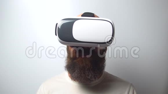 胡子男人使用虚拟现实头盔在白色背景虚拟现实虚拟现实眼镜高新技术视频的预览图