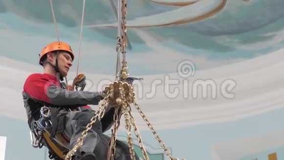 一个爬在梯子上的工业登山者正在准备提升设备的绳子戴防护头盔的工人编织视频的预览图
