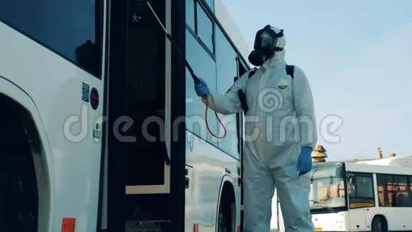 穿着防溅服的消毒剂正在给公共汽车出口消毒冠状病毒大流行概念消毒过程视频的预览图