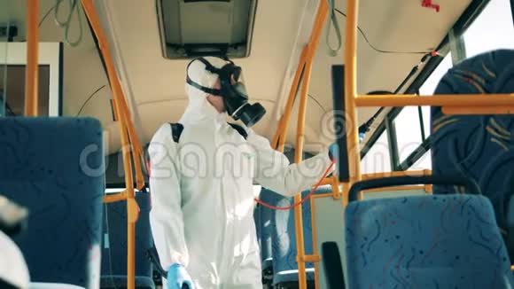一个穿防毒服的人正在给公共汽车内部消毒冠状病毒预防卫生消毒流程视频的预览图