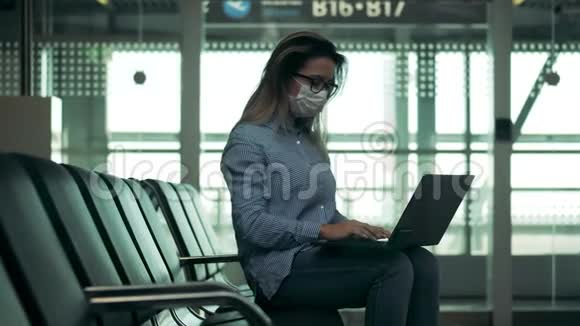 戴着医用面具的可爱女人用笔记本电脑视频的预览图