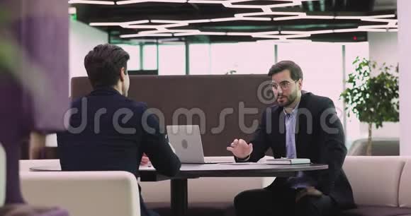 两个快乐的商业伙伴穿西装在办公室里握手视频的预览图