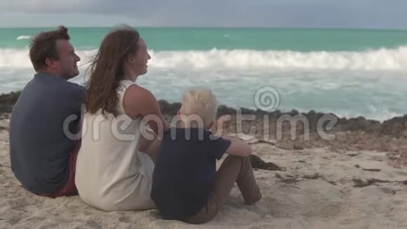 一家人坐在海边轻轻地拥抱着对方视频的预览图