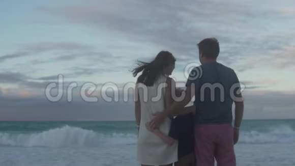 一家人拥抱在海滩上看着大海视频的预览图