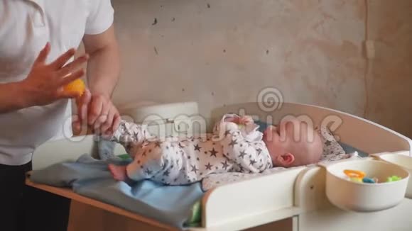 父亲照顾孩子的健康爸爸给他的新生婴儿做球按摩视频的预览图