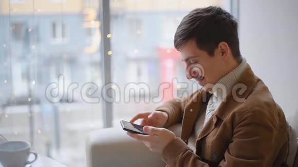 这家伙坐在咖啡馆里用智能手机写信息一个男人通过电话在社交网络上交流视频的预览图