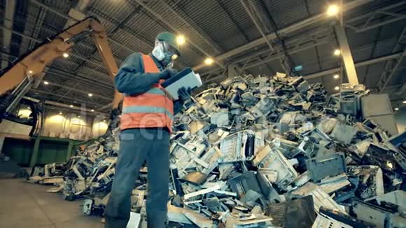 废弃的电子设备和一名垃圾填埋工人检查视频的预览图