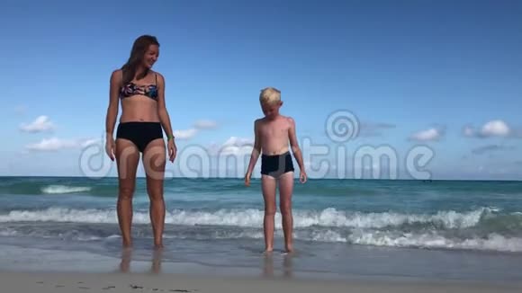 妈妈和儿子高兴地跳上海边视频的预览图